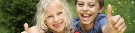 Zwei lachende Kinder zeigen den Daumen nach oben