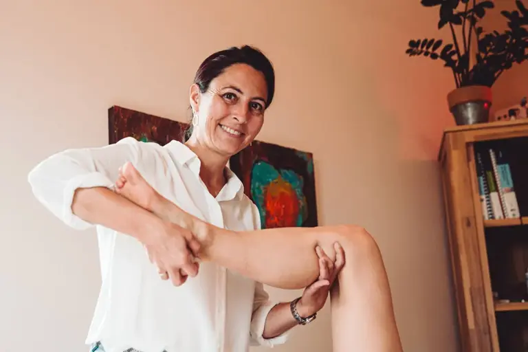 Physiotherapeutin bewegt bei der Behandlung das Bein einer Patientin