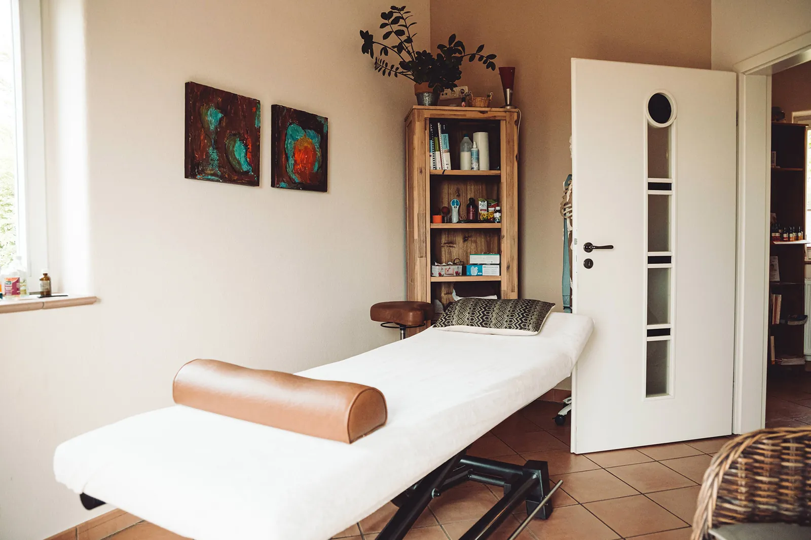 Therapieliege mit Nackenrolle vor einer Tür im Behandlungsraum