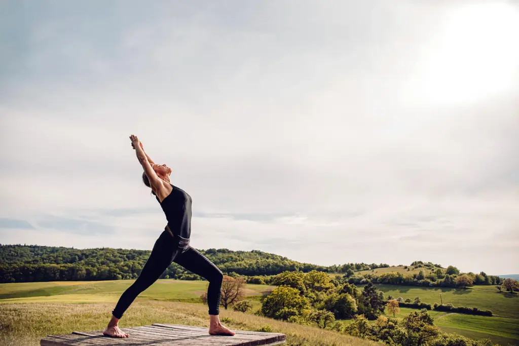 Heike Wagner in einer Yoga-Haltung im Freien über dem Steigerwald