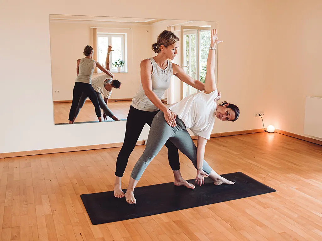 Heike Wagner korrigiert im Yoga Personal Training die Haltung eines Teilnehmers